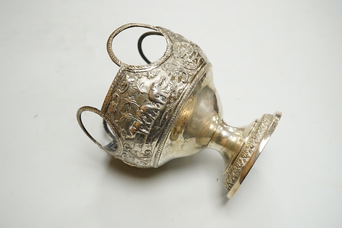 A late 19th/early 20th century Indian white metal pedestal bowl, with unusual ring handle border, embossed with continuous scene of wild animals, diameter 12.3cm, 6.3oz.